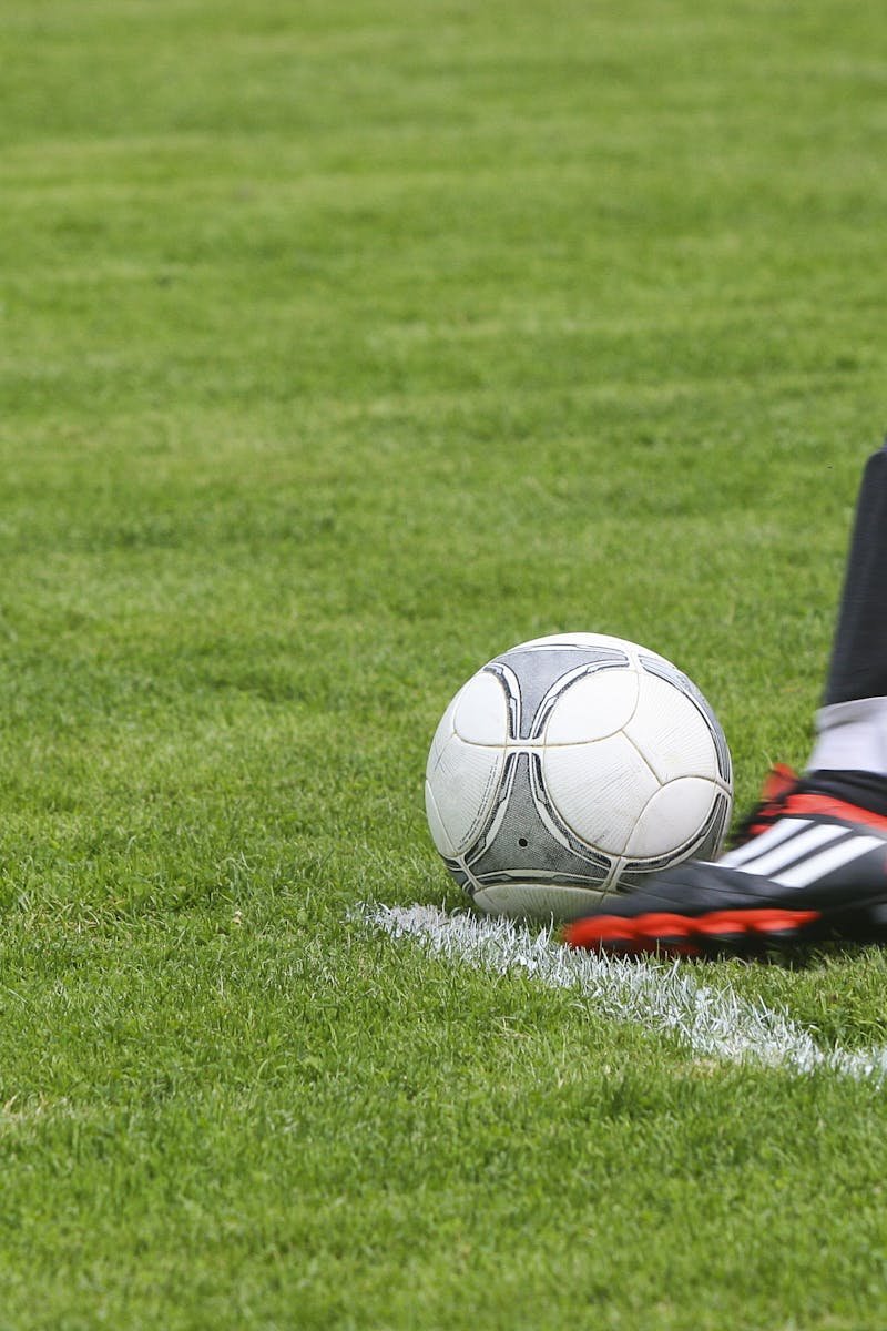Dynamic shot of a soccer player kicking the ball on a grassy field, showcasing fast-paced sports action.